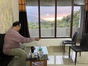 a man sitting in a room looking out of a window at Tapovan Fruitopia in Sultan Bathery