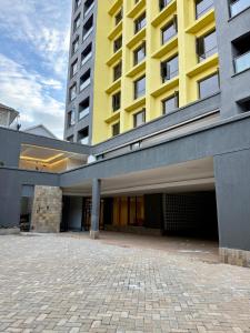 a large yellow and gray building with a parking lot at Kozi - Wilson Airport in Nairobi