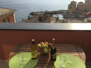 two bottles of wine and a bowl of fruit on a table at La Mansarda Sul Mare in Bogliasco