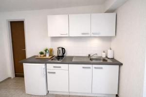 una cucina con mobili bianchi e un lavandino di Kleines Apartment mit Doppelbett a Coblenza