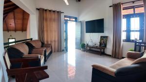 a living room with couches and a flat screen tv at Nomad's Peak Hiriketiya in Dickwella