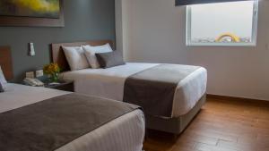 een hotelkamer met 2 bedden en een raam bij Eco Hotel Guadalajara Expo in Guadalajara