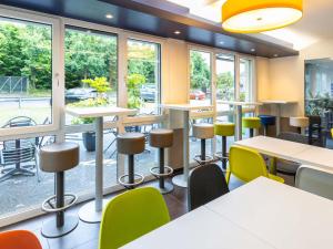 een cafetaria met tafels, stoelen en ramen bij ibis budget Basel Pratteln in Pratteln