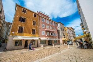 a woman walking down a cobblestone street with buildings at Accommodation Piazzetta Marina in Zadar