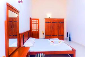 a bedroom with a bed and wooden furniture and a mirror at Bentota Backpackers Bay Hostel in Bentota