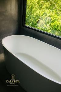 een badkamer met een wit bad en een raam bij Calypta Resort Phuket in Phuket