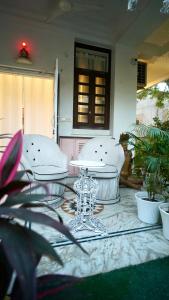 een patio met 2 witte stoelen en een tafel bij Lalluji Luxe in Jaipur