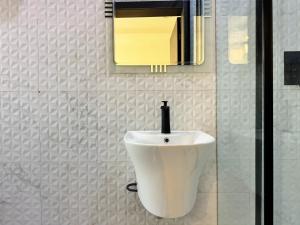a bathroom with a white sink and a mirror at The Colony in Mama