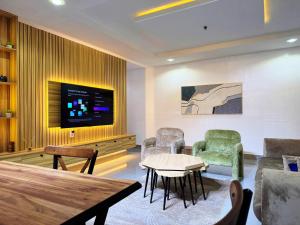 a living room with chairs and a table and a tv at The Colony in Mama
