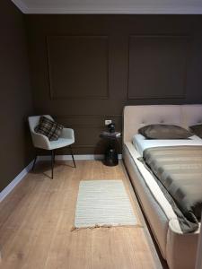 een slaapkamer met een bed, een stoel en een tapijt bij Cozy Central View in Reşiţa