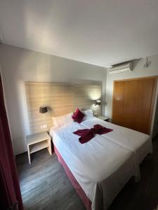 a bedroom with a large white bed with red flowers on it at Hotel Norai in Lloret de Mar