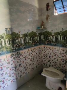 een badkamer met een toilet en een muur bedekt met dieren bij Laxmi Narasimha hotel in mayapur
