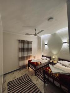 a bedroom with two beds and a ceiling fan at MERIT Guest House in Aswan