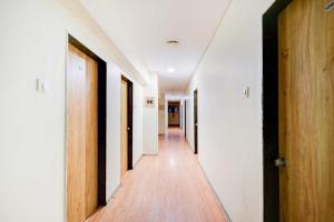 un couloir vide avec des murs blancs et du parquet dans l'établissement FabHotel White Ridge Chaitanyapuri, à Hyderabad