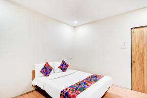 une chambre blanche avec un lit avec des oreillers colorés dans l'établissement FabHotel White Ridge Chaitanyapuri, à Hyderabad