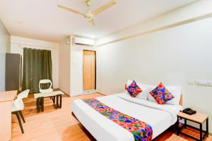 a bedroom with a large white bed and a desk at FabHotel White Ridge Chaitanyapuri in Hyderabad