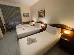 een hotelkamer met twee bedden met handdoeken erop bij Hotel Pavone in Milaan +28 foto's