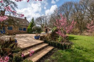 a garden with a stone house with pink flowers at 5 Bed in Hindolveston oc-d29357 in Hindolveston