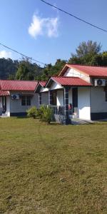 een wit huis met een rood dak en een tuin bij Mersing Chalet Teluk Sisek in Kampong Sisek