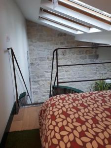 een slaapkamer met een bed en een stenen muur bij lapetitemaisondeparis in Parijs