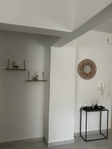 een kamer met een witte muur met een spiegel en een tafel bij Dafni Apartment Kozani in Kozani