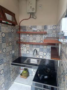 a kitchen with a sink and a tiled wall at Rumah Ramah Ubud in Ubud