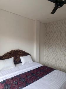 a bedroom with a bed with white sheets and a ceiling fan at Rumah Ramah Ubud in Ubud
