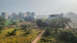 a dirt road in a field with buildings in the background at Laxmi Narasimha homestay in mayapur +19 photos