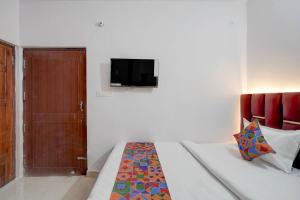 a bedroom with a bed with a tv on the wall at FabHotel Tree view Residency in Lucknow
