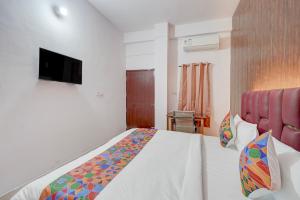 a bedroom with a bed and a tv on the wall at FabHotel Tree view Residency in Lucknow