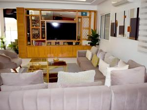 a living room with white couches and a flat screen tv at Villa Les Ambassades in Kenitra