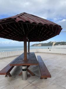 een picknicktafel met een parasol op het strand bij Ponta Negra Beach Melo Flat in Natal +5 foto's