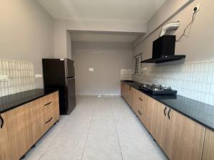 une cuisine avec des armoires en bois et un réfrigérateur noir dans l'établissement HomeSlice Sarjapur - Balcony Rooms, à Bangalore