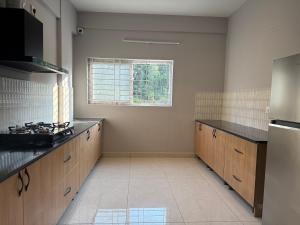 une grande cuisine avec des placards en bois et une fenêtre dans l'établissement HomeSlice Sarjapur - Balcony Rooms, à Bangalore