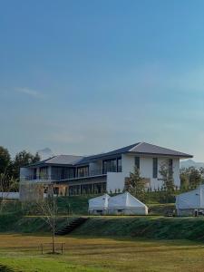 Rivendale في Ban Gaeng Cho: منزل أبيض كبير مع الخيام أمامه