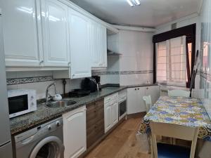 a kitchen with white cabinets and a table with a sink at Ca'Oviedo in Oviedo +15 photos