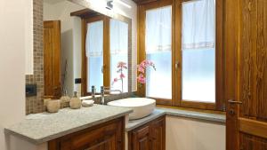 ein Bad mit einem Waschbecken, einem Spiegel und Fenstern in der Unterkunft Hostdomus - Chez Paul in Cesana Torinese