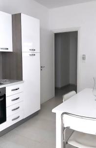 a kitchen with white cabinets and a white table at Aurea Suites in Palermo