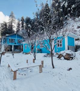 een blauw huis met een bank in de sneeuw bij High on hills in Kalgha