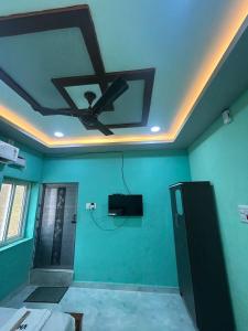 Cette chambre dispose d'un ventilateur de plafond et d'un mur vert. dans l'établissement Vacational Home Stay, à Rameswaram