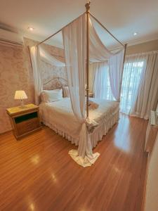 a bedroom with a canopy bed and a wooden floor at Pousada Ares da Serra - Centro in Gramado
