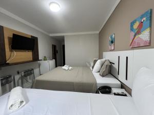 a small room with two beds and a tv at Ponta Negra Beach Melo Flat in Natal