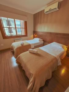 two beds in a hotel room with a window at Pousada Ares da Serra - Centro in Gramado