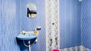 een blauw betegelde badkamer met een wastafel en een spiegel bij Gajalee Beach House in Bhogwe