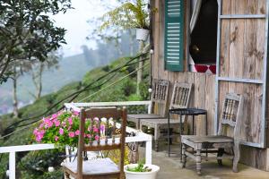 a porch of a house with chairs and flowers at Cỏ Mây Wonder Homestay in Mộc Châu