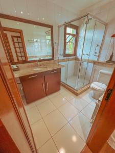 a bathroom with a toilet and a glass shower at Pousada Ares da Serra - Centro in Gramado