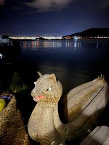 Eine Schlangenstatue sitzt neben einem Gewässer. in der Unterkunft Uros bungalows TITICACA in Puno