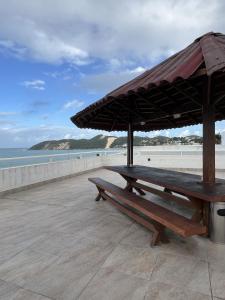 een picknicktafel met een parasol op het strand bij Ponta Negra Beach Melo Flat in Natal