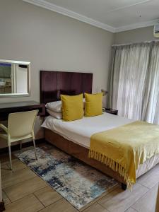 een slaapkamer met een bed met gele kussens en een stoel bij Cozy Corner in Bloemfontein