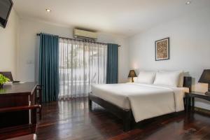 een slaapkamer met een groot wit bed en een bureau bij Apsara Centrepole Hotel in Siem Reap +116 foto's